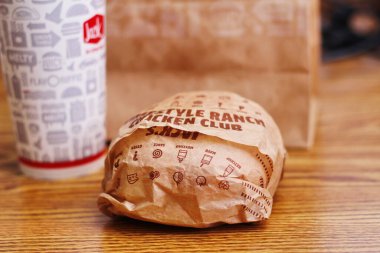 WASHINGTON, USA - JULY 29 2022 : A home-style rance chiken club burger on a wooden table with soft drinks in a jack in the box restaurant in the USA.
