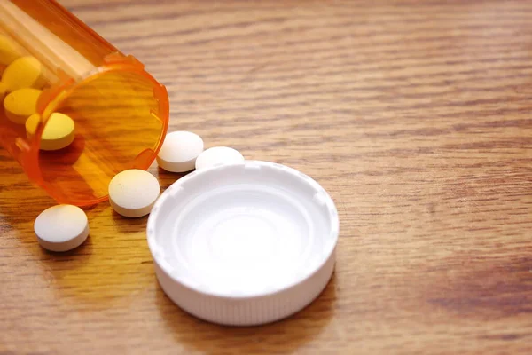 Pills were poured from the orange pill bottle onto the wooden table, medicine pill on wooden table..