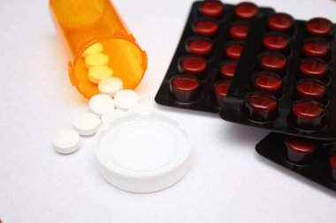 Pills, pill packs and pill bottles placed on a white background
