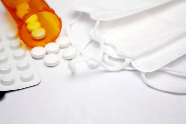 Pills, pill boxes and pill bottles, white mask placed on a white background.