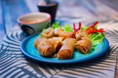 Deep fried spring rolls in blue plates with vegetables, chili and dipping sauce (Chinese food) in thailand