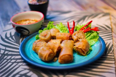 Deep fried spring rolls in blue plates with vegetables, chili and dipping sauce (Chinese food) in thailand