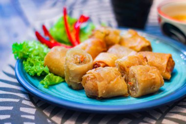 Deep fried spring rolls in blue plates with vegetables, chili and dipping sauce (Chinese food) in thailand