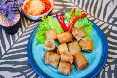 Deep fried spring rolls in blue plates with vegetables, chili and dipping sauce (Chinese food) in thailand