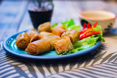 Deep fried spring rolls in blue plates with vegetables, chili and dipping sauce (Chinese food) in thailand