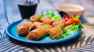 Deep fried spring rolls in blue plates with vegetables, chili and dipping sauce (Chinese food) in thailand