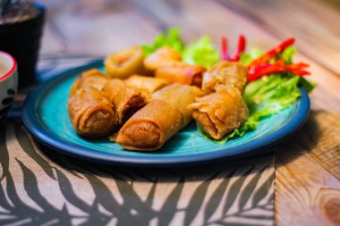 Deep fried spring rolls in blue plates with vegetables, chili and dipping sauce (Chinese food) in thailand