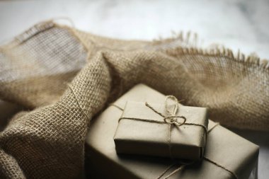 Gift box wrapped in brown recycled paper placed on a white table