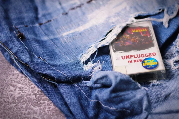 stock image WASHINGTON, USA - September 30 2022 : Nirvana's cassette tape and Ripped jeans or Torn jeans. A symbol of the grunge or Seattle sound.