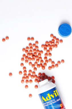 Washington, ABD - 02 Ekim 2022: Advil şişeleri ve haplar beyaz bir masaya yayıldı. Ateş, ağrı kesici, popüler Amerikan ağrı kesici, ibuprofen..