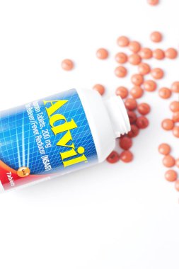 Washington, ABD - 02 Ekim 2022: Advil şişeleri ve haplar beyaz bir masaya yayıldı. Ateş, ağrı kesici, popüler Amerikan ağrı kesici, ibuprofen..