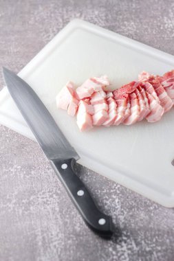 Seri domuz eti mutfakta beyaz bir doğrama tahtasıyla dilimlenir. Domuzu çiğ olarak kes.