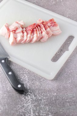 Seri domuz eti mutfakta beyaz bir doğrama tahtasıyla dilimlenir. Domuzu çiğ olarak kes.