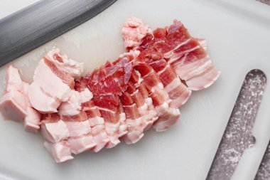 Seri domuz eti mutfakta beyaz bir doğrama tahtasıyla dilimlenir. Domuzu çiğ olarak kes.