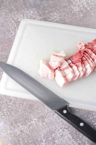 Seri domuz eti mutfakta beyaz bir doğrama tahtasıyla dilimlenir. Domuzu çiğ olarak kes.