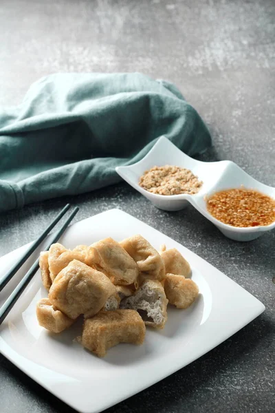 Fried tofu served in a white plate with tamarind sauce and mashed beans, fried tofu is a popular dish among Chinese and Asians.
