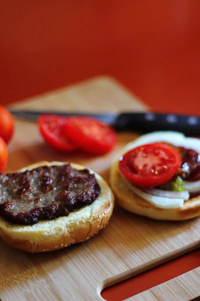 Hamburger Jest Przygotowywany Podawany Pokrojonymi Pomidorami Cebulą Ogórkami Drewnianej Desce — Zdjęcie stockowe