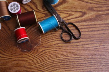 Ahşap bir masaya saçılmış renkli iplikler ve eski makas, retro makas, düz yatış, kopyalama alanı.