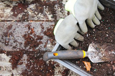 Topraklı saksılar ekime ve eldivenlere hazırlandı. Ahşap bir balkona konmuş turşu, toprakla dağılmış..