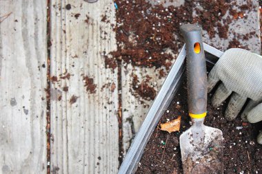 Topraklı saksılar ekime ve eldivenlere hazırlandı. Ahşap bir balkona konmuş turşu, toprakla dağılmış..