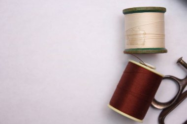 Beyaz zemine yayılmış çok renkli iplikler ve eski makas, retro makas, düz konum, kopyalama alanı.