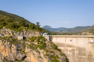 Bu manzara fotoğrafı Avrupa 'da, Fransa' da, Provence Alpes Cote dAzur 'da yaz mevsiminde çekilmiştir. Dik kayalıklara kurulmuş Barrage de Castillon 'u görebiliyoruz, güneşin altında..