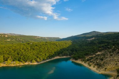 Bu manzara fotoğrafı Avrupa 'da, Fransa' da, Provence Alpes Cote dAzur 'da yaz mevsiminde çekilmiştir. Sainte-Croix Gölü 'nü ve onun yeşil ormanlarını, güneşin altında görebiliriz..