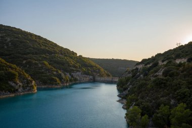 Bu manzara fotoğrafı Avrupa 'da, Fransa' da, Provence Alpes Cote dAzur 'da yaz mevsiminde çekilmiştir. Ormanların ortasındaki gölde, güneşin altında Sainte-Croix barajını görebiliyoruz..