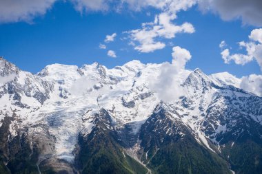 Bu manzara fotoğrafı Avrupa 'da, Fransa' da, Alpler 'de, yazın Chamonix' e doğru çekildi. Mont Blanc Massif 'i Aiguillette des Houches' a bakan bulutların arasında Mont Blanc Massif 'de, güneşin altında görebiliyoruz..