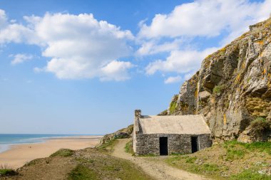 Bu manzara fotoğrafı ilkbaharda Avrupa, Fransa, Normandiya, Manche 'de çekildi. Güneşin altında Cap de Carteret sahiline bakan taştan bir ev görüyoruz..