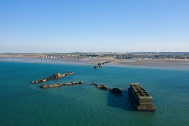 Bu manzara fotoğrafı yazın Avrupa, Fransa, Normandiya, Arromanches les Bains 'de çekildi. Asnelles 'deki yapay Gold limanının kalıntılarını görebiliyoruz. Güneşin altında..