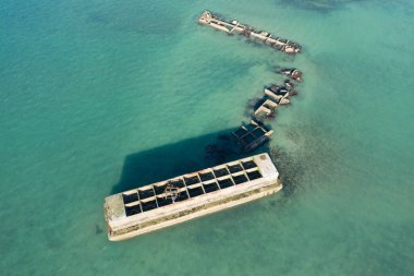 Bu manzara fotoğrafı yazın Avrupa, Fransa, Normandiya, Arromanches les Bains 'de çekildi. Asnelles 'deki yapay altın limanını İngiliz Kanalı' nın ortasında, güneşin altında görebiliyoruz..