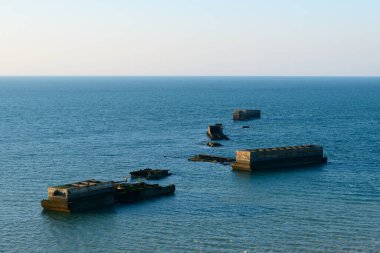 Bu manzara fotoğrafı yazın Avrupa, Fransa, Normandiya, Arromanches les Bains 'de çekildi. Amerikan yapay limanının yüzen beton elementlerini görüyoruz, güneşin altında..