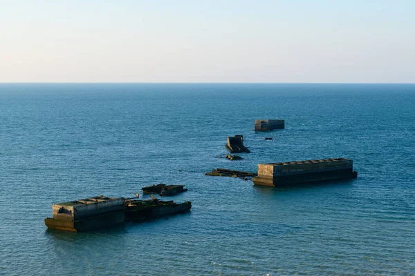 Bu manzara fotoğrafı yazın Avrupa, Fransa, Normandiya, Arromanches les Bains 'de çekildi. Amerikan yapay limanının yüzen beton elementlerini görüyoruz, güneşin altında..