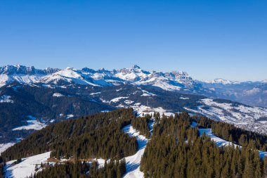 Bu manzara fotoğrafı Avrupa 'da, Fransa' da, Rhone Alpes 'te, Savoie' de, Alpler 'de, kışın çekildi. Megeve 'in kayak yamaçlarını Mont Blanc' ın dağlarının ortasında, güneşin altında görüyoruz..
