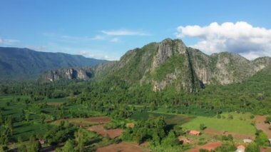 Asya 'da bir dağın eteğindeki yeşil pirinç tarlaları ve tropikal ormanlar, Laos, Khammouane, güneşli bir günde Thakek ve Konglor' a doğru.