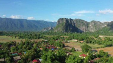 Güneşli bir günde, Asya 'daki dağların eteklerindeki tropikal ormanın ortasındaki geleneksel bir köy olan Laos, Khammouane, Thakek ve Konglor' a doğru..