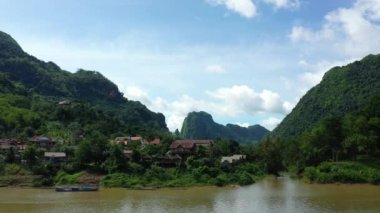 Nam Ou nehri kıyısındaki Nong Khiaw köyü Asya 'daki yeşil dağlarla çevrili, Laos, yazın güneşli bir günde, Luang Prabang' a doğru..