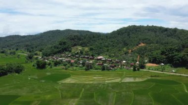 Yazın güneşli bir günde, Vientiane ve Luang Prabang arasında, Asya 'nın yeşil kırsalındaki pirinç tarlalarının ortasında bir köy, Laos..