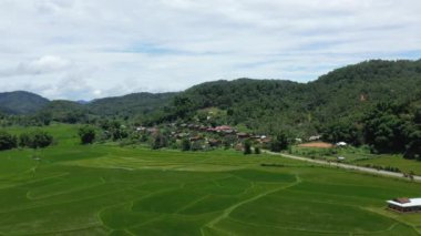 Yazın, güneşli bir günde, Vientiane ve Luang Prabang arasında, Asya 'da ormanlarla ve yeşil dağlarla çevrili geleneksel bir köyün ortasında bir yol..