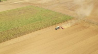 Bir traktör yazın güneşli bir günde Fransa 'nın Avrupa kırsalında çorak bir tarlayı sürüyor..