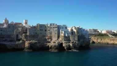 Polignano a Mare 'nin Avrupa, İtalya ve Puglia' daki kayalıkların kenarındaki evleri güneşli bir günde Bari 'ye doğru düşerler..
