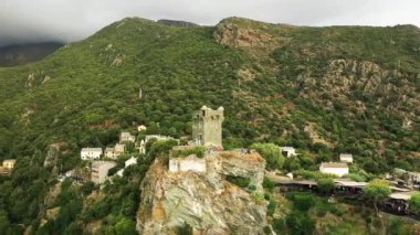 The village of Nonza in the middle of the arid and green mountains, in Europe, in France, in Corsica, towards Bastia, by the Mediterranean Sea, in summer, during a cloudy day.