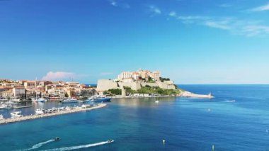 Calvi şehri ve yeşil dağların eteklerindeki ortaçağ kalesi, Avrupa, Fransa, Korsika, Akdeniz kıyısında, yazın güneşli bir günde.