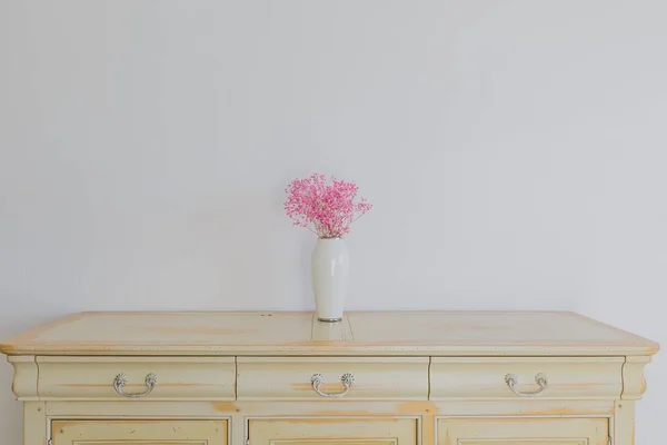 Vazodaki pembe çiçek şifoniyerin üzerinde duruyor. Stok Fotoğraf