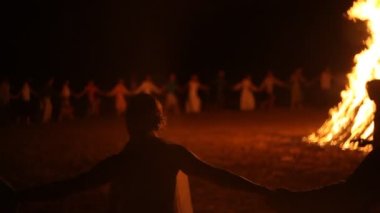 People dance around a big bonfire at night 