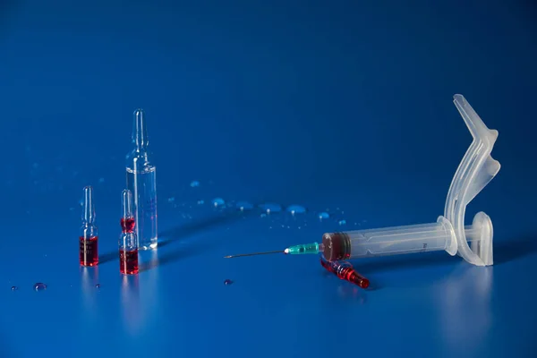 Seringa e medicamentos encontram-se no fundo azul — Fotografia de Stock