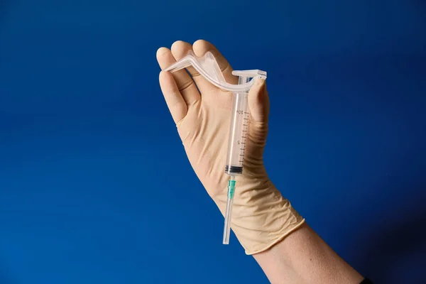 青の背景に手袋をはめた手の注射器 — ストック写真