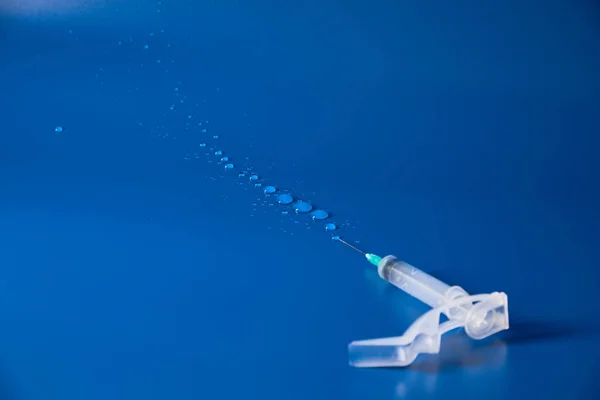 Jeringa y gotas de medicamento se encuentran sobre fondo azul — Foto de Stock