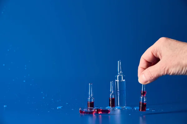Medicinali con liquido rosso si trovano su sfondo blu — Foto Stock